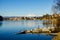 Landscape with an Italian village and mountains along a river with a small sunken boat on a clear winter day. Sesto Calende, Italy