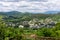 Landscape of Kutaisi rural outskirts with traditional residential buildings, green lush vegetation and hills around, summer,