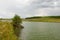 landscape with a lake and green banks in cloudy weather