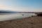 Landscape of a lake with a happy dog or mongrel running. Beautiful sky with clouds during sunset. Sandy beach. Free time. Free tim