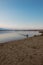 Landscape of a lake with a happy dog or mongrel running. Beautiful sky with clouds during sunset. Sandy beach. Free time. Free tim