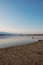 Landscape of a lake with a happy dog or mongrel running. Beautiful sky with clouds during sunset. Sandy beach. Free time. Free tim