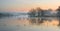 Landscape of lake in mist with sun glow at sunrise