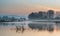 Landscape of lake in mist with sun glow at sunrise