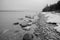 Landscape of lake shoreline with snow and stones bw