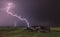 Landscape with lightning striking behind dead tree trunk