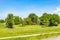 a landscape in Lower Saxony with green meadows. Almost hidden from trees stands a typical house for this region