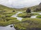 Landscape with lush green grass and moss, water stream and lagoon and lava rock in Iceland central mountain