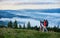 Landscape of mighty mountains with slight haze and tourists with backpacks walking holding hands along mountain path