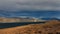 Landscape with Mountain Hills and Lake Bathed in Sunlight. Dark Cloudy Sky.