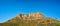 Landscape of a mountain peak in Cape Town, South Africa. Rugged mountaintop with green shrubs, grass, trees and a blue