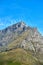 Landscape of mountains and a blue sky with copy space. Rock outcrops of a mountain with wild green plants, bushes and