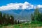 Landscape with mountains, lush green grass, lift and large caps of clouds over the mountain tops in Krasnaya Polyana, Sochi