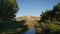 Landscape with narrow river flowing through lush green vegetation in Canadian Badlands