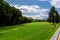 Landscape of a nature reserve with a lamppost and a lantern on a green lawn glade.