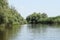 Landscape on a navigable canal surrounded by vegetation in the Danube Delta during a beautiful sunny day with blue sky. Cruising