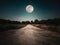 Landscape of night sky and bright full moon. Asphalt road leading into the forest at night. Serenity background