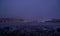 Landscape of a night, winter, foggy city: lanterns, light in the Windows of houses, snow-covered trees and grass