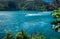 Landscape with ocean, lighthouse, mountains, tree branch, purple flowers. Tasman Bay, Nelson area, New Zealand