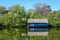 Landscape with old blue house and many large old green trees trees on the shoreline of Herastrau Lake in King Michael I Park in