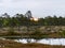 Landscape with old peat bogs and swamp vegetation. The bog pond reflects small pines, bushes and cloudy skies. Niedraju Pilkas