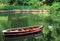 Landscape with old row boat and swan on lake in forest in summer