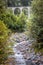 Landscape with old viaduct in forest, Filisur, Switzerland. Scenic vertical view of high railway bridge and rocky brook in Alps