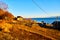 Landscape with old wooden house near lake with blue water and sky. Lake Baikal. A tourist sightseeing train moves along the Circum