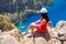 Landscape Oludeniz, Turkey, a young girl in a red dress looks at the Butterfly Valley from above, sitting on the rocks