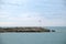 Landscape with open Mediterranean sea and the entrance to the marina with Turkish flag on flagpole on the edge in the overcast day