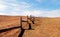 Landscape of pasture for cattle, wooden fence in prairie, blue sky with clouds.