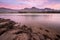 A landscape photograph of a beautiful mountain range and golden pink clouds after sunset