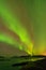 A landscape photograph with water and mountains, with a beautiful green Northern Light display in a dark star studded sky