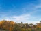 Landscape photography trees and bushes with yellow and green leaves with a tower crane in the background and a lip-blue sky with