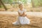 Landscape portrait of cute laughing 6 years old girl sitting at the ground outdoors