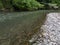 Landscape of rapids of river Ukrina with gravel beach and tree branches leaned over water