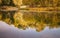 Landscape reflected in a forest autumn lake in retro style, under film