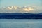 Landscape of the right bank of Lake Zurich with snowy peaks of Alps on the horzizon and cumulus clouds.