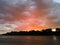 Landscape with river, colorful clouds and forested shore at sunset. Dramatic riverine scene during cloudy dusk with rain or summer