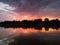 The landscape of the river after the storm during the summer evening at sunset, the reflection in the water, the dark dramatic