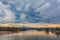 Landscape of river with trees and overcast skies at dusk.