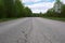 Landscape with a road damaged by asphalt, trees and sky