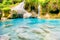 Landscape of rock cascades of waterfall with stones in blue lake in jungle forest, Erawan, Thailand