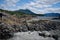 Landscape of rocky shore, gravel beach and distant mountains with beached kayaks