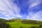 Landscape scenery of green valley with trees, hill and cloudy sky