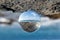Landscape of sea and rocks through a glass ball