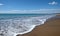 Landscape with sea, surf, sandy beach and high mountains at far