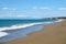 Landscape with sea, surf, sandy beach and high mountains at far