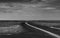 Landscape of sea at tide and grey sky and white clouds along the winding water canal. Mud flat at coast. Black and white picture