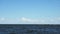 Landscape of the sea with waves on windy summer day with lighthouse on the background in timelapse